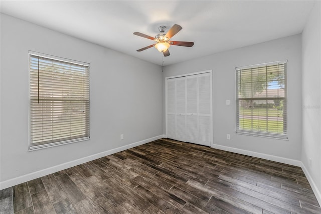 unfurnished bedroom with dark wood-type flooring, a closet, a ceiling fan, and baseboards