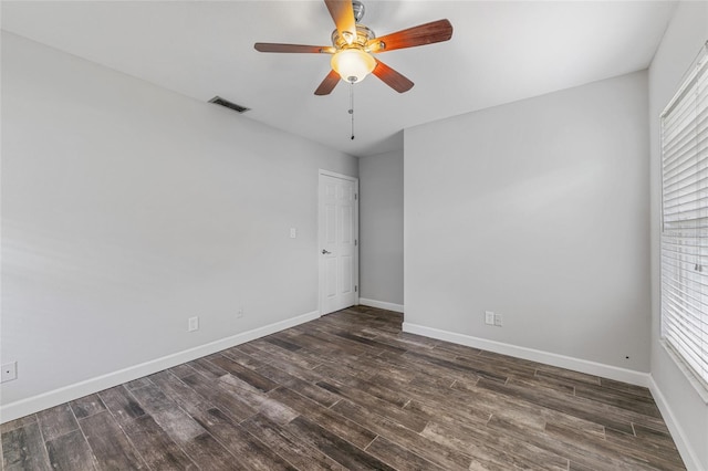 spare room with a ceiling fan, dark wood-style flooring, visible vents, and baseboards