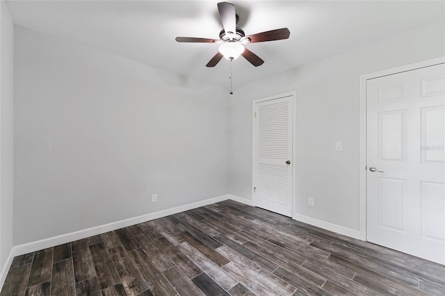 empty room with dark wood-style floors, ceiling fan, and baseboards