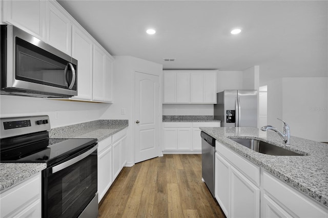 kitchen with dark wood finished floors, stainless steel appliances, visible vents, white cabinets, and a sink