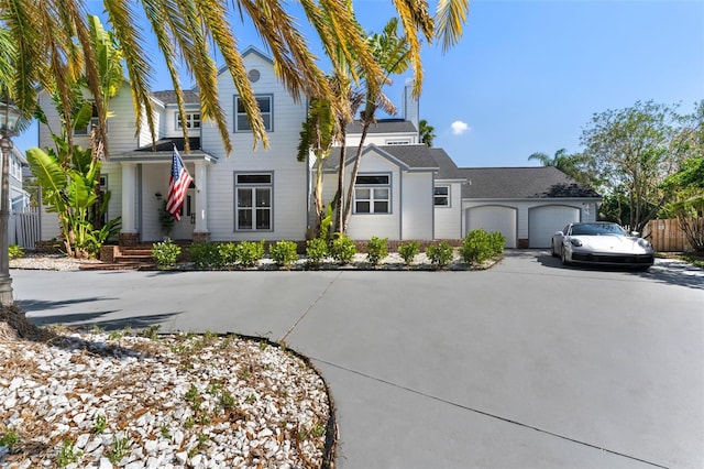 view of front of property with concrete driveway, an attached garage, and fence