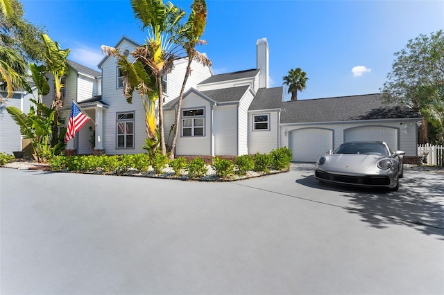 view of front of property featuring a garage, a chimney, and concrete driveway