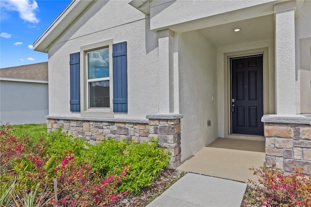 doorway to property featuring stone siding and stucco siding