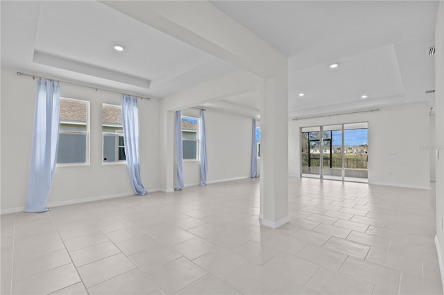 unfurnished room featuring light tile patterned floors, a tray ceiling, and baseboards