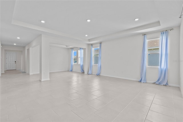 interior space with light tile patterned floors, baseboards, a tray ceiling, and recessed lighting