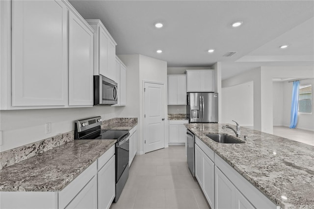 kitchen featuring appliances with stainless steel finishes, white cabinets, a sink, and recessed lighting