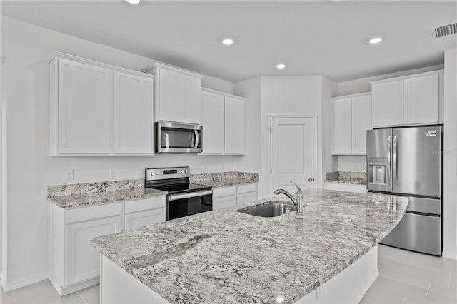 kitchen featuring stainless steel appliances, a sink, visible vents, white cabinets, and an island with sink