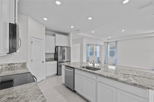 kitchen featuring stainless steel appliances, a sink, visible vents, white cabinets, and light stone countertops