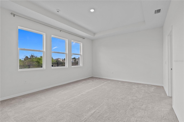 unfurnished room featuring carpet floors, a raised ceiling, visible vents, and baseboards