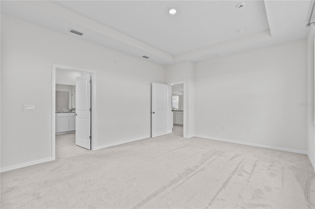 unfurnished bedroom featuring baseboards, a raised ceiling, visible vents, and light colored carpet