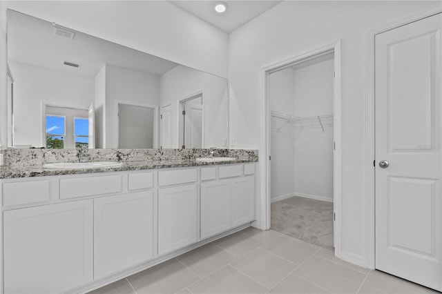 bathroom with double vanity, a sink, visible vents, and a walk in closet