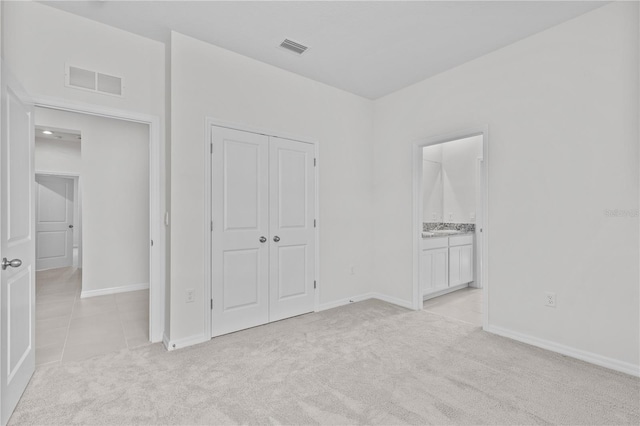 unfurnished bedroom featuring a closet, visible vents, light carpet, and baseboards