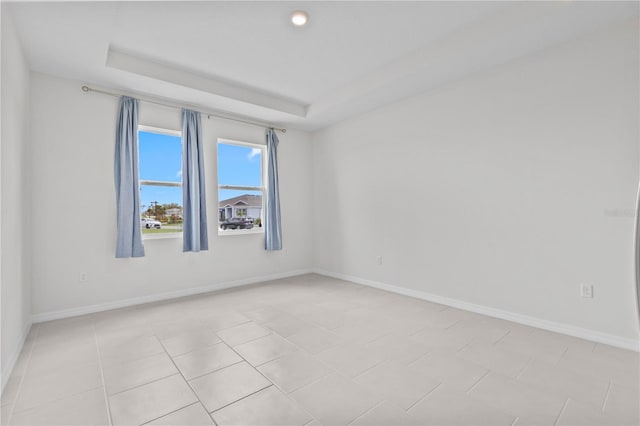 unfurnished room with baseboards and a raised ceiling