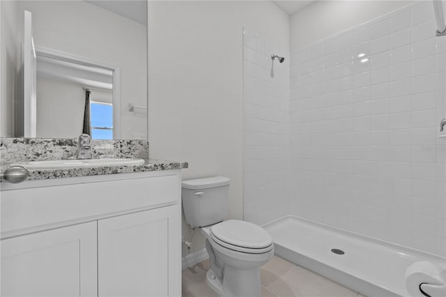 bathroom with vanity, tile patterned flooring, a tile shower, and toilet