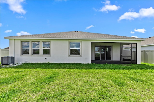 back of property featuring a yard, stucco siding, a sunroom, central AC, and fence