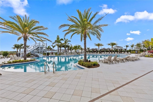 community pool featuring a water slide and a patio