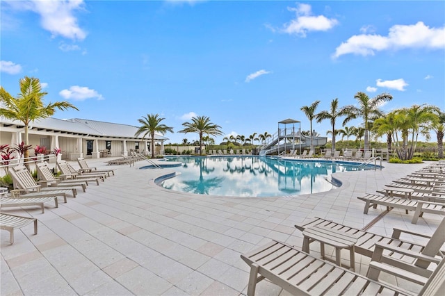 community pool featuring a patio and a water slide