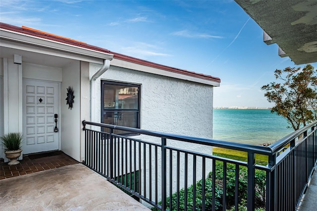 exterior space featuring a balcony, a water view, and stucco siding