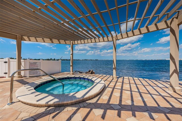 view of swimming pool with a patio area, a water view, fence, and a hot tub