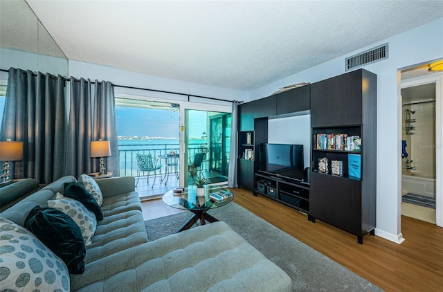 living room featuring visible vents, a textured ceiling, and wood finished floors