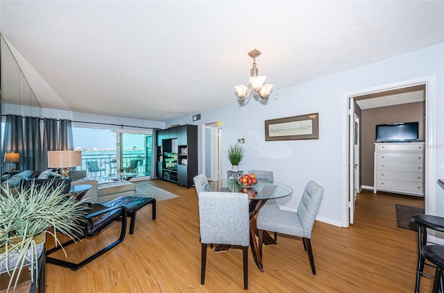 dining space featuring a chandelier, baseboards, light wood-style flooring, and a textured ceiling