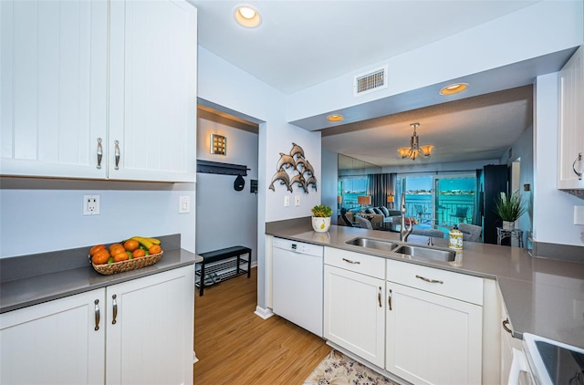 kitchen with visible vents, light wood-style floors, white cabinets, a sink, and dishwasher