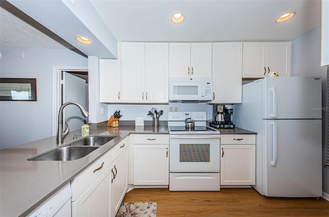 kitchen featuring white appliances, white cabinetry, a sink, and recessed lighting