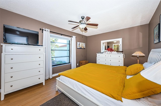 bedroom with a textured ceiling, wood finished floors, and a ceiling fan