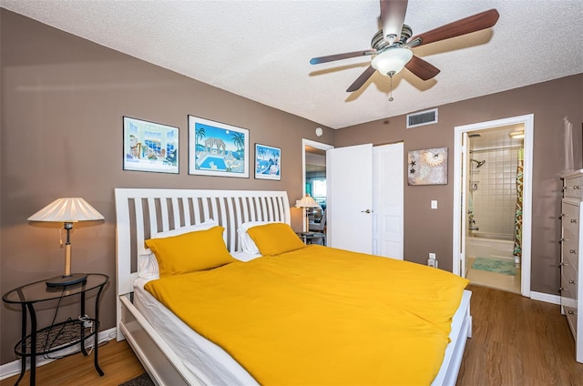 bedroom featuring baseboards, visible vents, connected bathroom, wood finished floors, and a textured ceiling