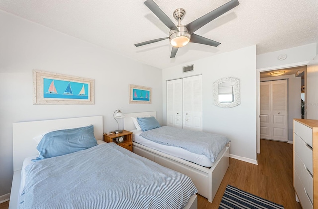 bedroom featuring ceiling fan, wood finished floors, visible vents, baseboards, and a closet