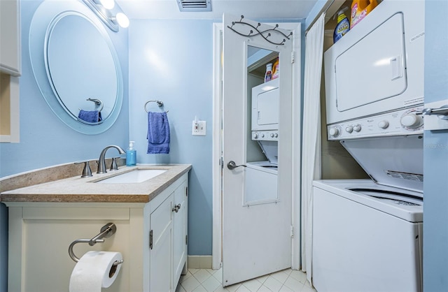 bathroom with stacked washer and dryer, visible vents, vanity, baseboards, and tile patterned floors