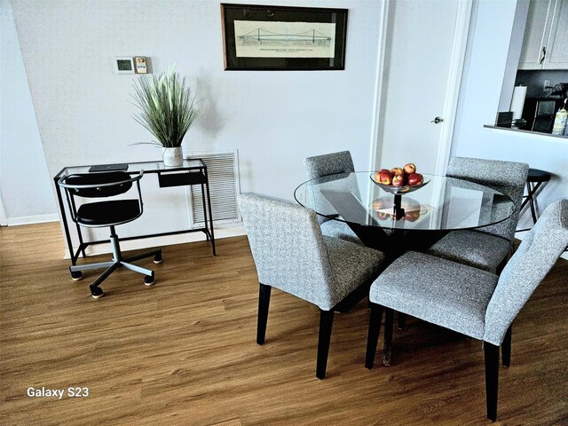 dining space with wood finished floors, visible vents, and baseboards