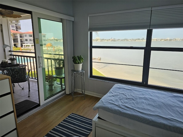 bedroom featuring access to outside, multiple windows, baseboards, and wood finished floors