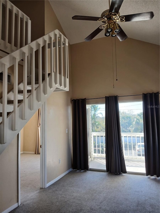 carpeted empty room featuring high vaulted ceiling, ceiling fan, and baseboards