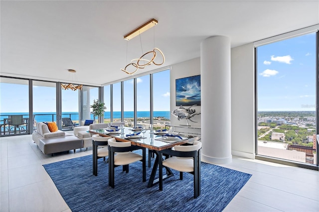 dining area featuring expansive windows, a water view, a wealth of natural light, and a notable chandelier