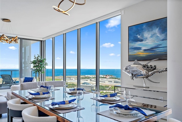 dining room featuring plenty of natural light, floor to ceiling windows, a water view, and an inviting chandelier