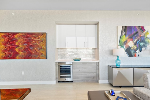 bar with a bar, beverage cooler, baseboards, and decorative backsplash