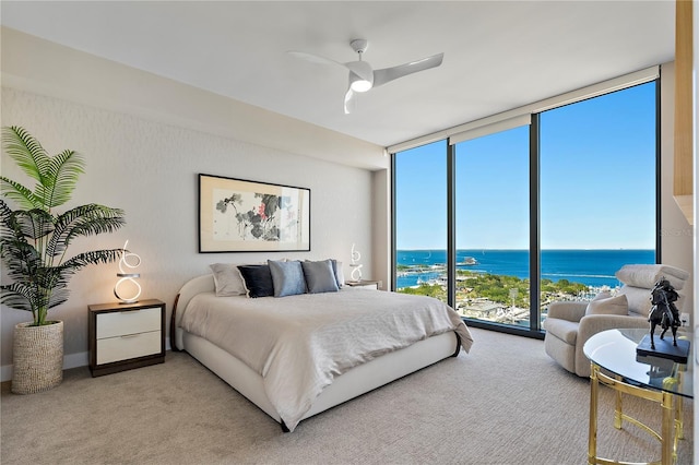 carpeted bedroom featuring a water view, ceiling fan, and floor to ceiling windows