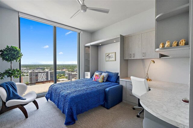 carpeted bedroom with a wall of windows and a ceiling fan