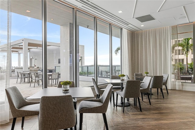 dining space with floor to ceiling windows and wood finished floors