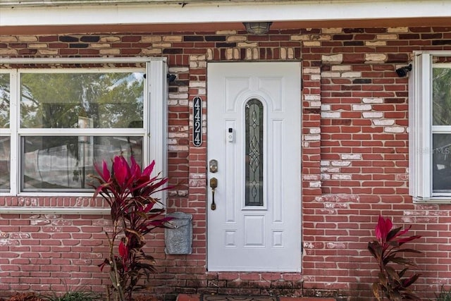 doorway to property featuring brick siding