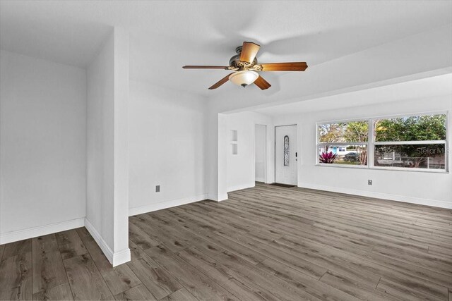 unfurnished living room with a ceiling fan, baseboards, and wood finished floors