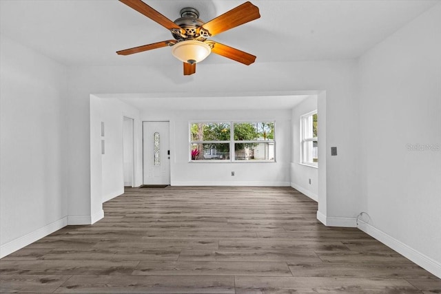 unfurnished living room featuring ceiling fan, baseboards, and wood finished floors