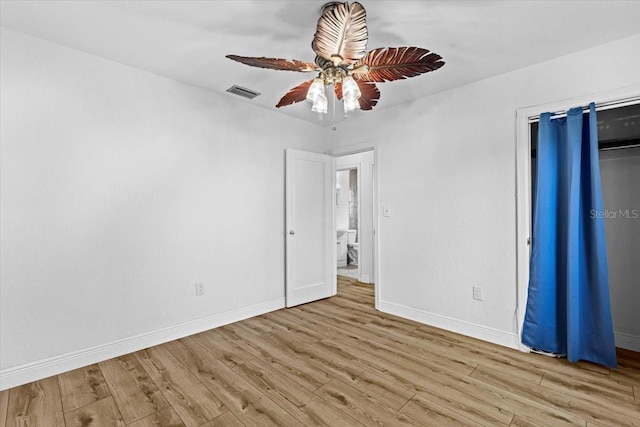 unfurnished bedroom featuring a ceiling fan, wood finished floors, visible vents, and baseboards