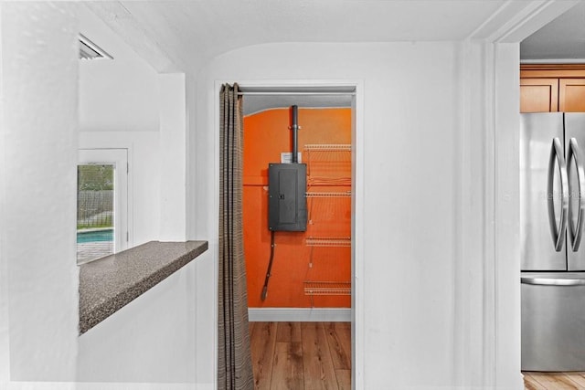 interior space featuring freestanding refrigerator, wood-type flooring, electric panel, and visible vents