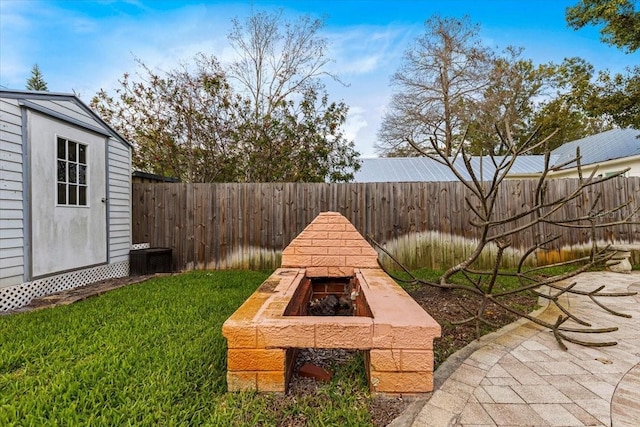 view of yard with a patio, a storage unit, a fenced backyard, an outdoor structure, and a fire pit