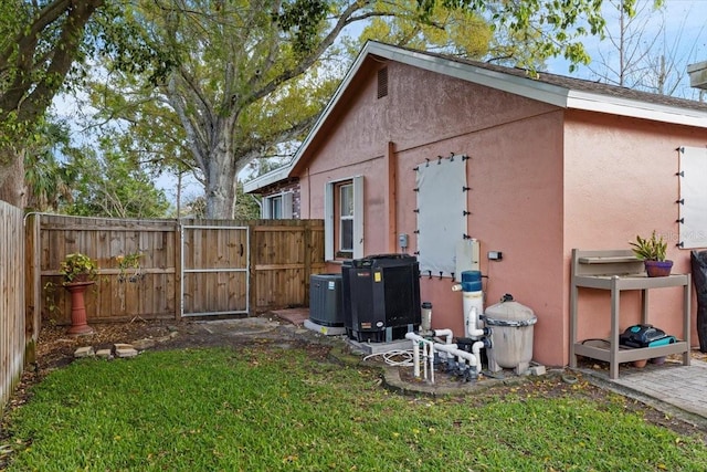 view of side of property with a yard, fence, and stucco siding