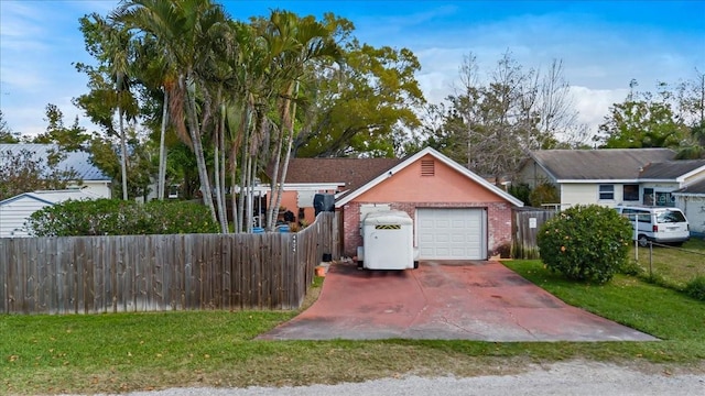 view of front of home featuring brick siding, a detached garage, a front lawn, and fence