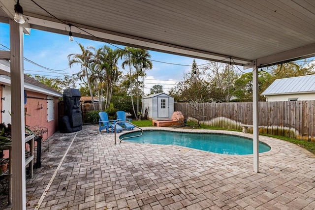 view of pool with an outbuilding, a fenced backyard, a shed, and a patio