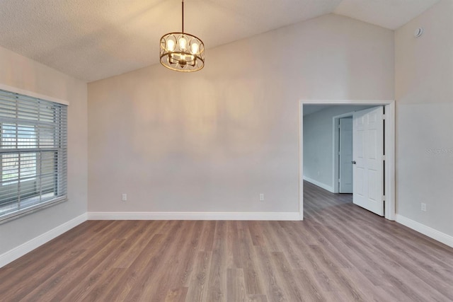 empty room with lofted ceiling, wood finished floors, and baseboards